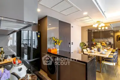 Luxurious modern kitchen with sleek appliances and elegant dining area in open layout apartment.