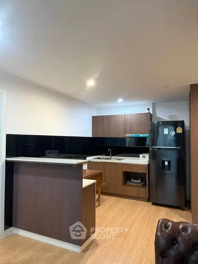 Modern kitchen with sleek design, featuring wooden cabinetry and black appliances, perfect for culinary enthusiasts.