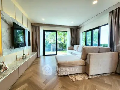 Spacious living room with large windows and modern decor, overlooking a lush garden.