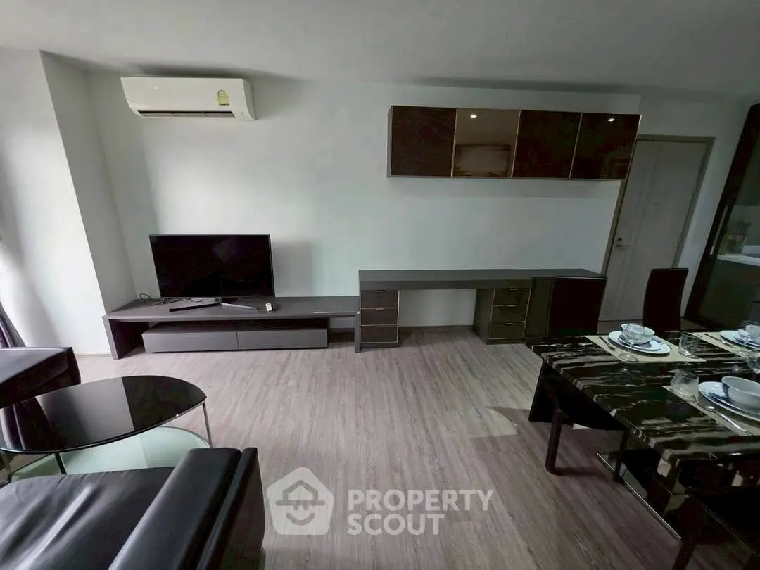 Modern living room with sleek furniture and dining area, featuring air conditioning and stylish decor.