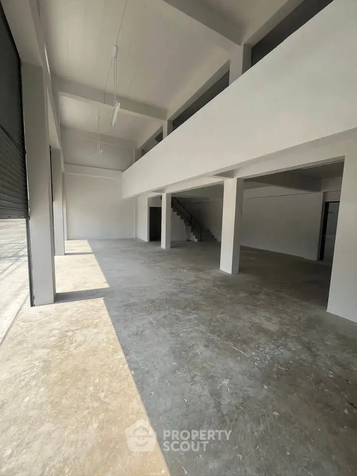 Spacious industrial-style open space with high ceilings and mezzanine, perfect for creative or commercial use.
