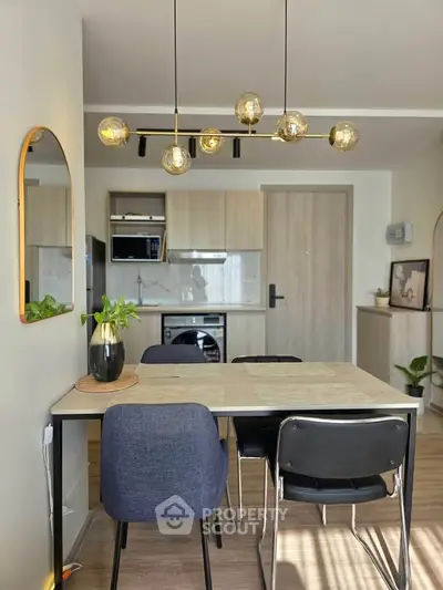 Modern dining area with stylish lighting and open kitchen layout in a cozy apartment.