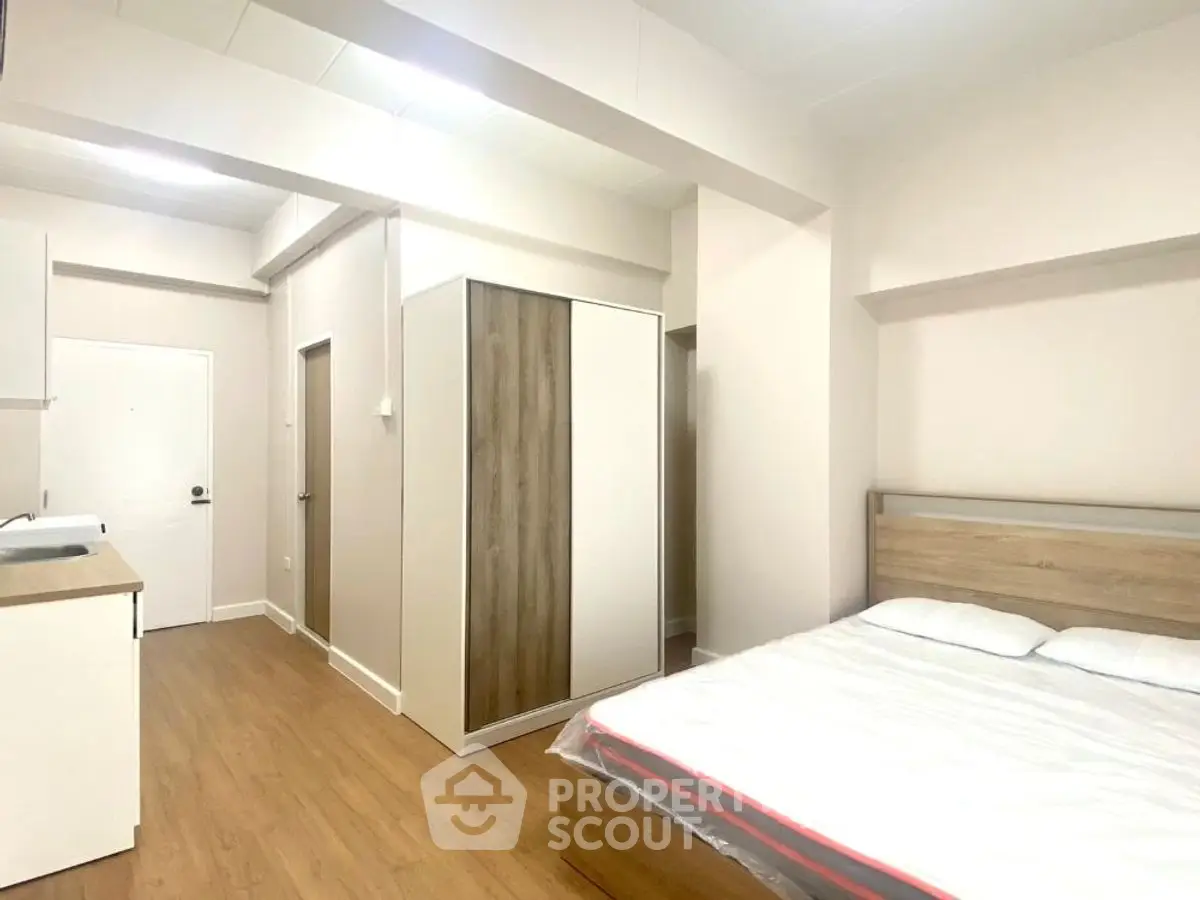 Spacious modern bedroom with wooden flooring and sleek wardrobe design.