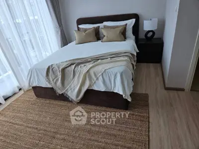 Elegant bedroom with cozy bed, stylish decor, and natural light from large windows.