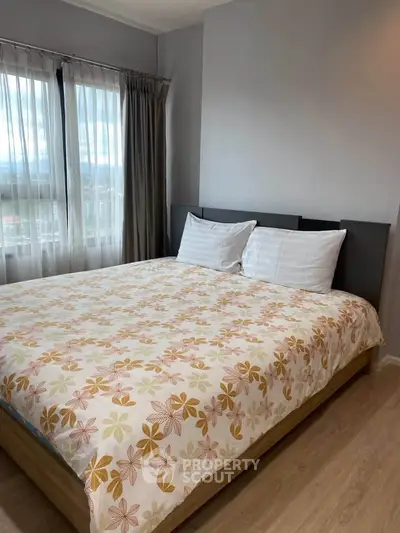 Cozy bedroom with large window and floral bedding in modern apartment.