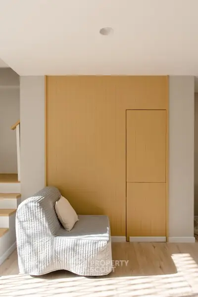 Modern living room with stylish sofa and wooden accent wall, featuring natural light and minimalist design.