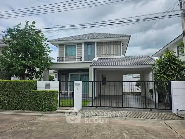 Modern two-story house with gated driveway and lush greenery