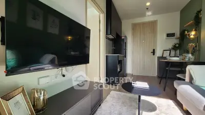 Modern living room with sleek TV, cozy seating, and stylish decor in a compact apartment.