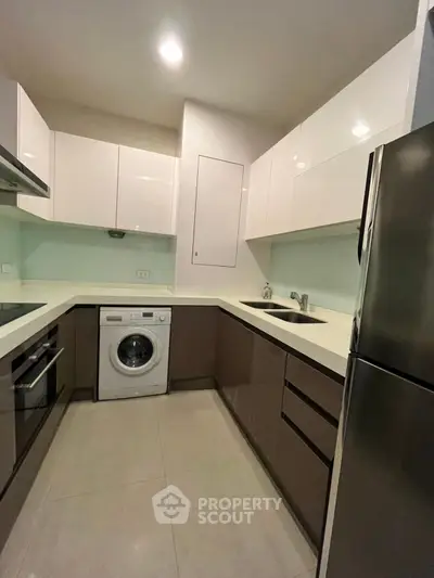 Modern kitchen with sleek cabinetry, built-in appliances, and washing machine in compact layout.