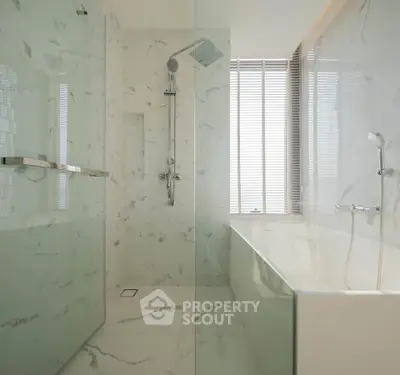 Luxurious modern bathroom with marble finishes and spacious shower area.