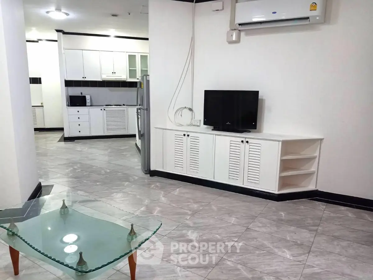 Spacious living room with modern kitchen and sleek glass coffee table