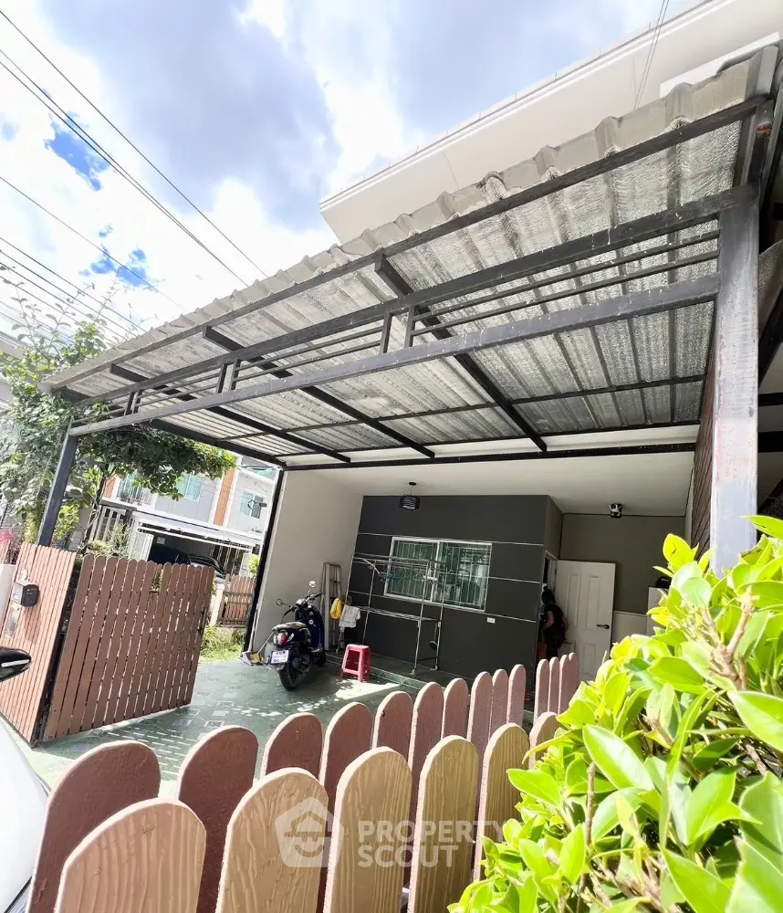 Modern carport with metal roof and wooden fence in suburban home