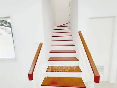Modern minimalist staircase with wooden steps and white walls in a bright interior space.