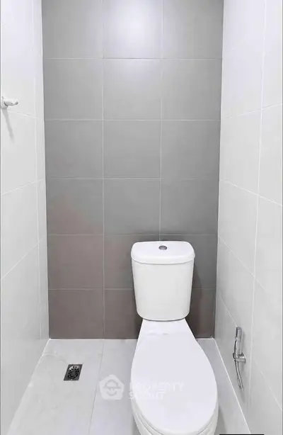 Modern minimalist bathroom with sleek gray and white tiles and a compact toilet.