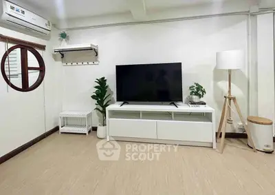 Modern living room with sleek TV stand, stylish decor, and wooden flooring.