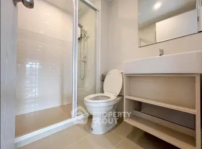 Modern bathroom with glass shower and sleek vanity in contemporary home.