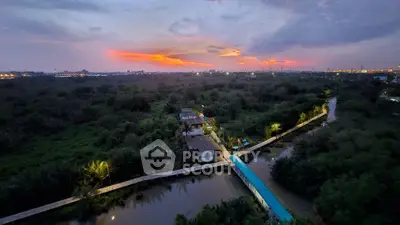 Stunning aerial view of lush greenery and serene waterway at sunset, perfect for tranquil living.