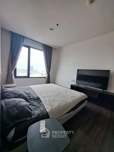 Modern bedroom with large window and flat-screen TV, offering a cozy and inviting atmosphere.