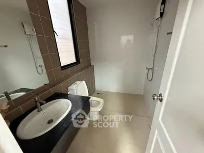 Modern bathroom with sleek fixtures and neutral tiles, featuring a shower and a stylish sink.