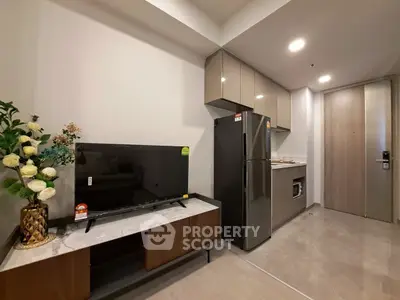Modern kitchen with sleek cabinets, stainless steel fridge, and elegant TV setup in a stylish apartment.