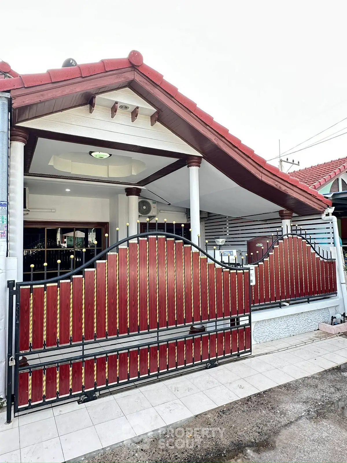 Charming single-story home with red-tiled roof and decorative gated entrance.