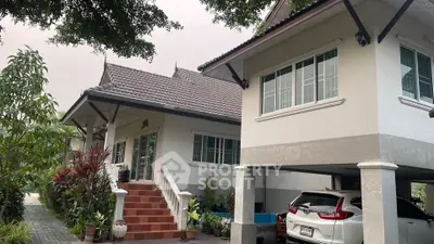 Charming two-story house with carport and lush garden, featuring traditional architectural elements and spacious outdoor area.