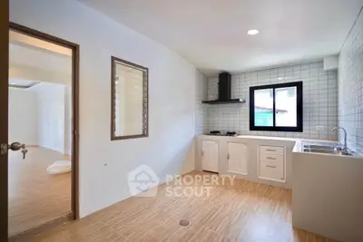 Modern kitchen with gas stove and ample natural light, featuring sleek cabinetry and tiled backsplash.