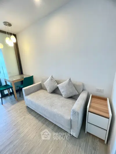 Modern living room with cozy gray sofa and stylish dining area in open layout apartment.