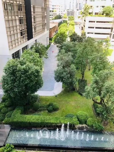 Lush garden view with modern building and water feature in urban setting.