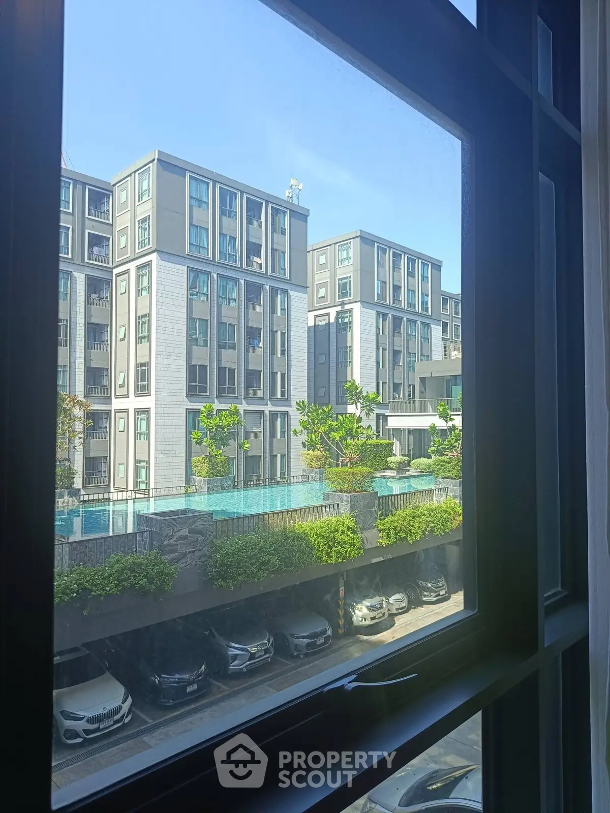 Modern apartment complex view from window with pool and parking area