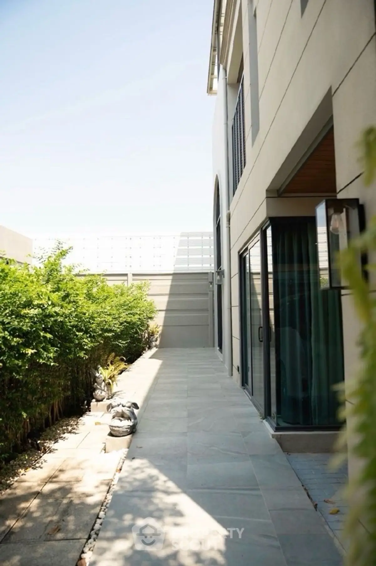 Modern exterior walkway with lush greenery and sleek architectural design.