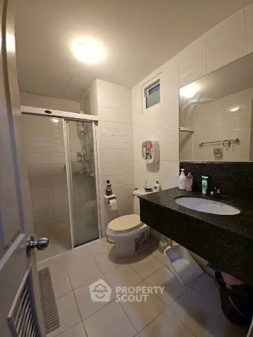 Modern bathroom with sleek black countertop and glass shower enclosure