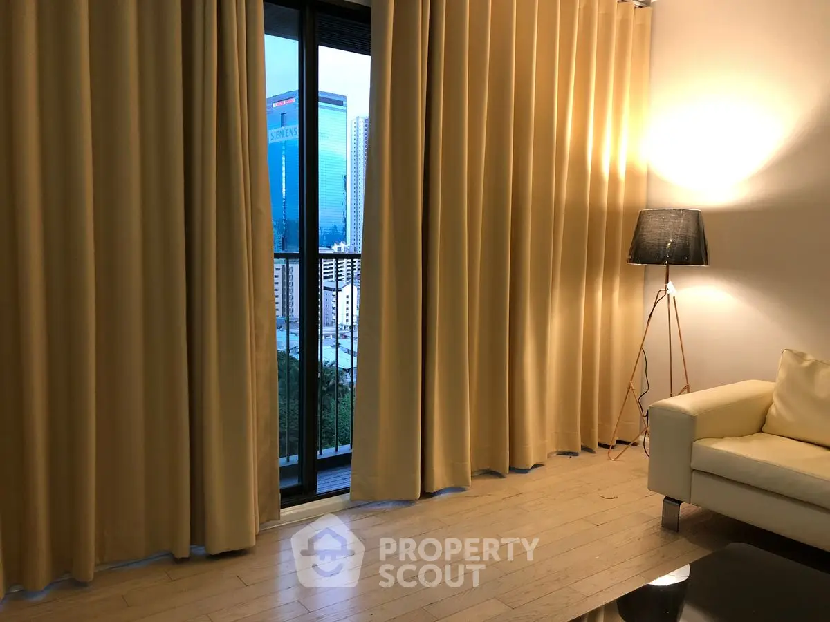Cozy living room with floor-to-ceiling curtains and city view from balcony.