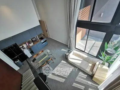 Stunning loft-style living room with high ceilings and large windows, featuring modern furniture and abundant natural light.