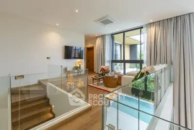 Luxurious modern living room with large windows and elegant decor, featuring a stylish staircase and natural light.
