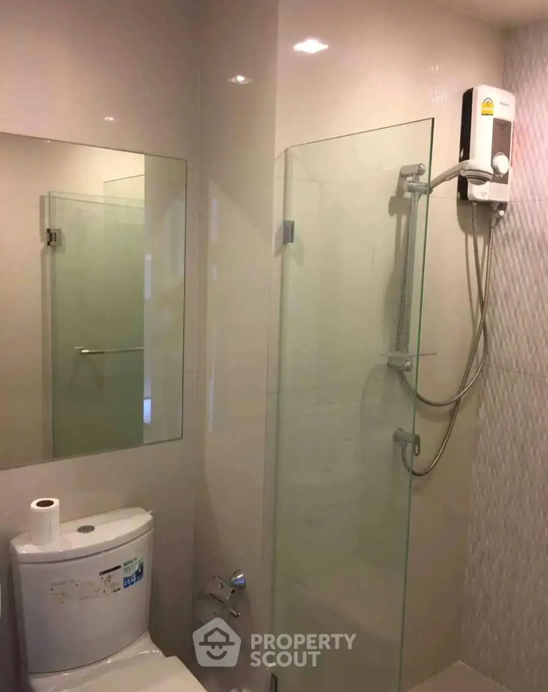 Modern bathroom with glass shower and water heater in sleek apartment.