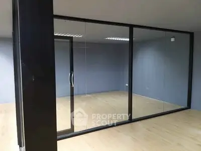Modern office space with glass partitions and wooden flooring, ideal for a professional work environment.