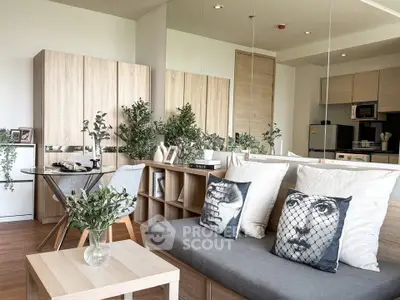 Modern living room with stylish decor and open kitchen layout, featuring unique art pillows and lush greenery.