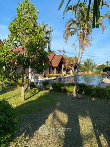 Tropical resort with lush gardens and inviting pool under clear blue skies.