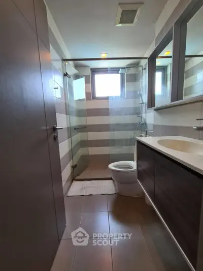 Modern bathroom with glass shower and sleek vanity in stylish apartment.