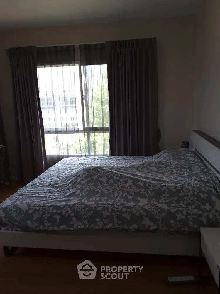 Cozy bedroom with large window and elegant curtains, perfect for relaxation.