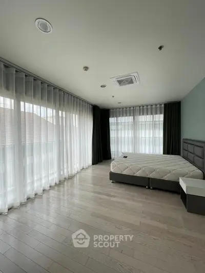 Spacious bedroom with large windows and modern design in a luxury apartment.