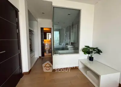 Modern bedroom with glass partition and ensuite bathroom, featuring sleek design and wooden flooring.