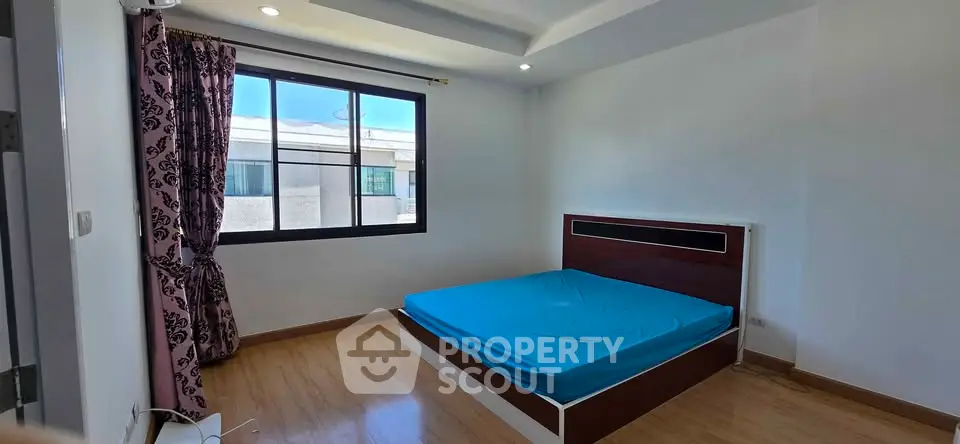 Spacious bedroom with large window and modern design in a bright apartment.