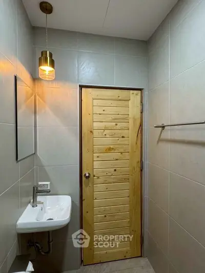 Modern bathroom with wooden door and stylish lighting fixture