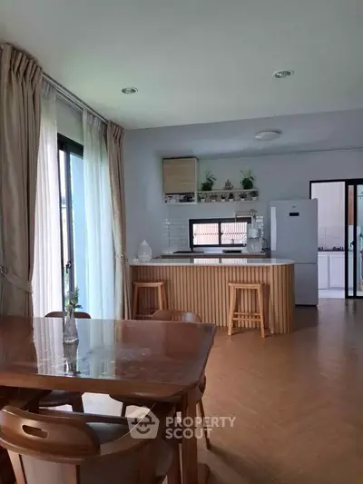 Modern kitchen with open layout and dining area, featuring stylish wooden accents and natural light.