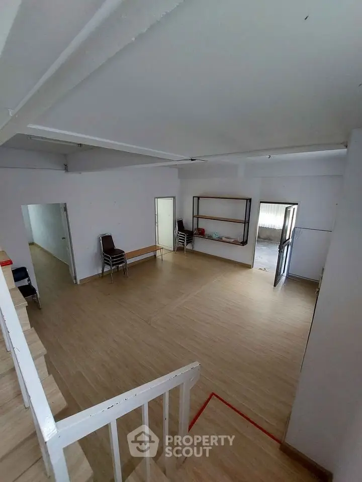 Spacious open-plan interior with wooden flooring and ample natural light, ideal for versatile living or office space.