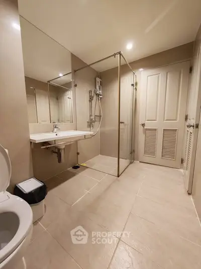 Modern bathroom with glass shower enclosure and sleek fixtures in a contemporary apartment.