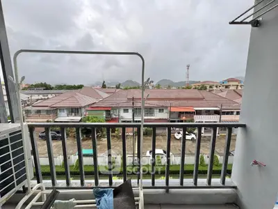 Charming balcony view overlooking residential neighborhood with scenic hills in the background.