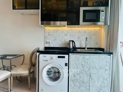 Modern kitchen with marble finish, washing machine, microwave, and elegant dining area.